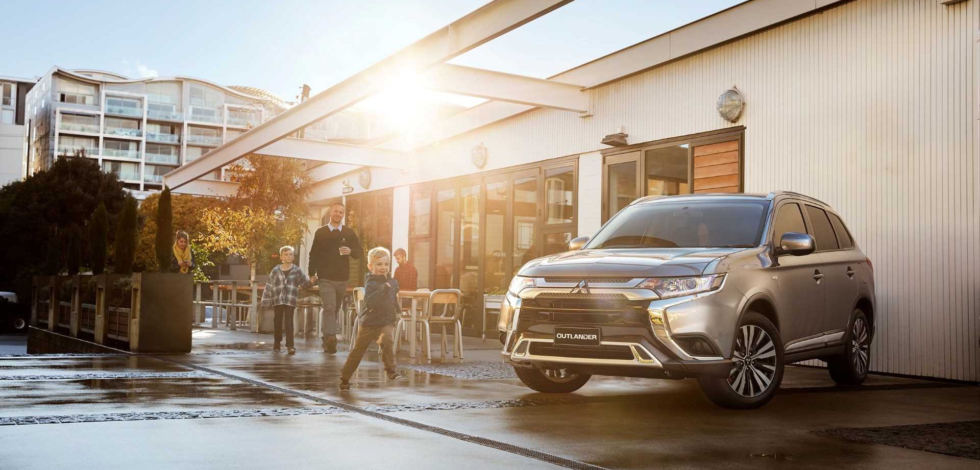 A new Mitsubishi Outlander parked in front of a building.