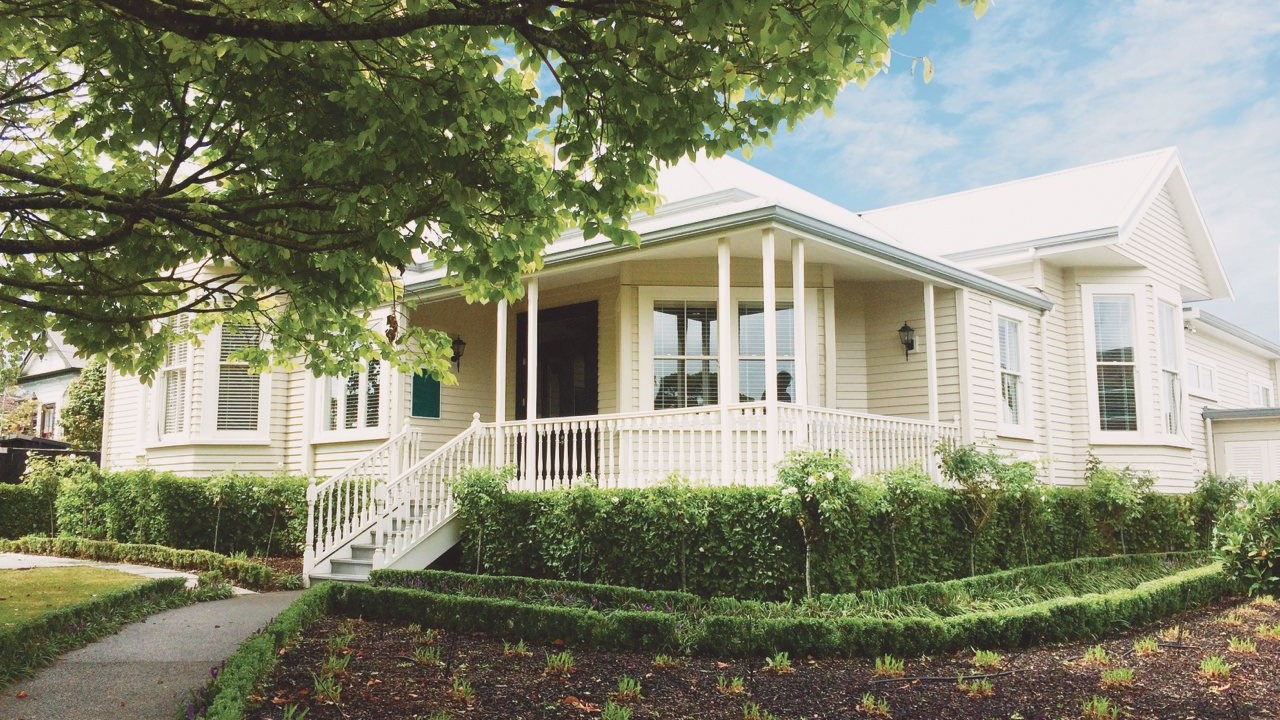 A house with a white porch and a green lawn.