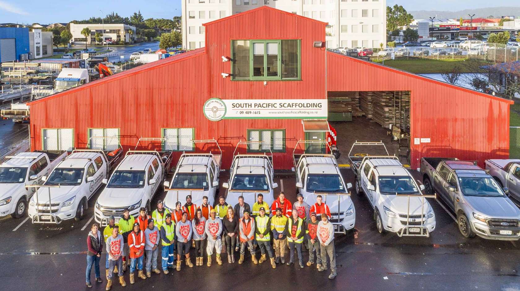 People standing in front of red building.